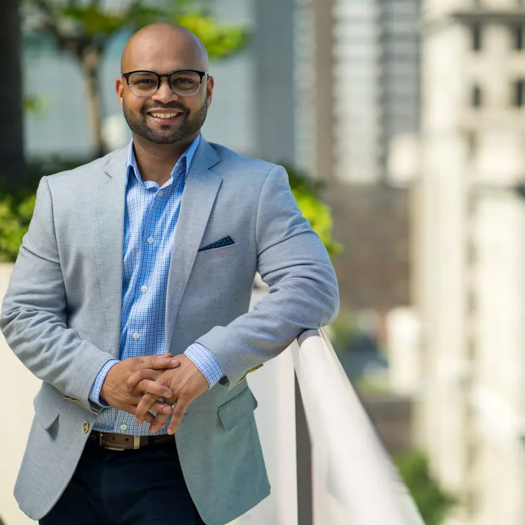 Sheldon Rodrigues in a blazer with the city skyline behind him