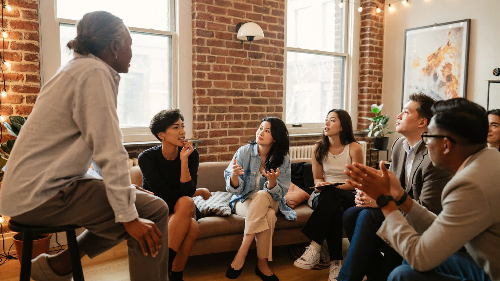 A small group talking together on sofas in a brick loft