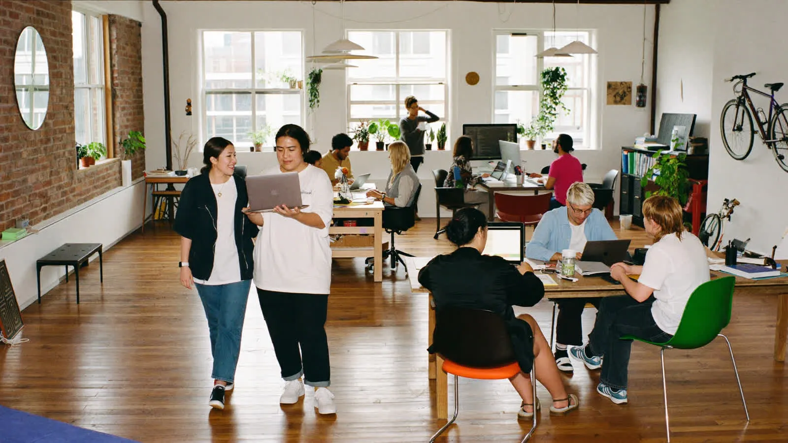 People working and talking side by side in a bright loft studio